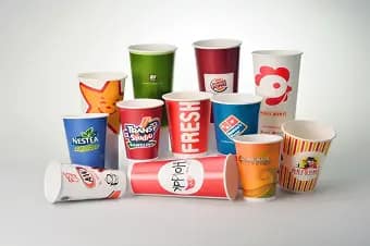 Berbagai macam cangkir kertas untuk minuman dingin atau cold paper cup berwarna-warni dengan desain unik dan logo merek, termasuk warna hijau, merah, hitam, dan putih, cocok untuk minuman dingin.